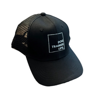 Black cap with 'Dog Trainer Life' text on a wooden floor